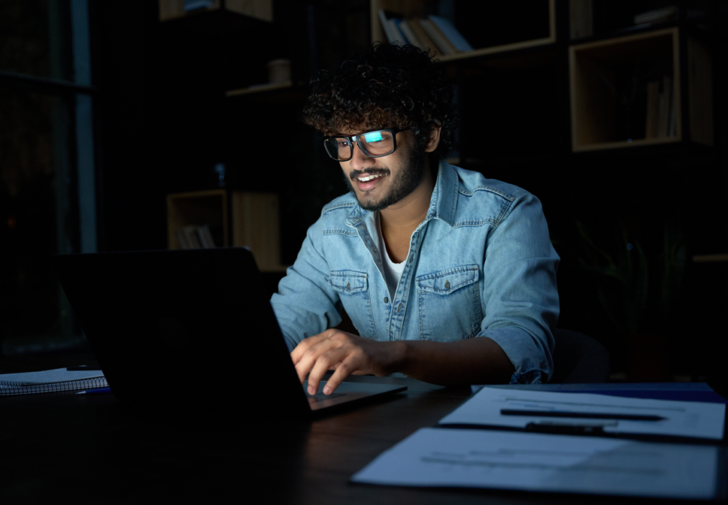 Mann arbeitet nachts konzentriert am Laptop in einem modernen Büro